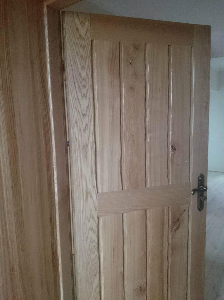 drewniane drzwi z czarną klamką