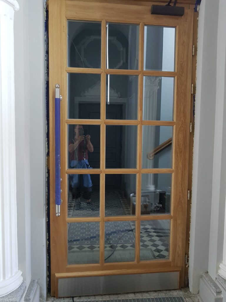 jasne drewniane drzwi ze szklaną kratką