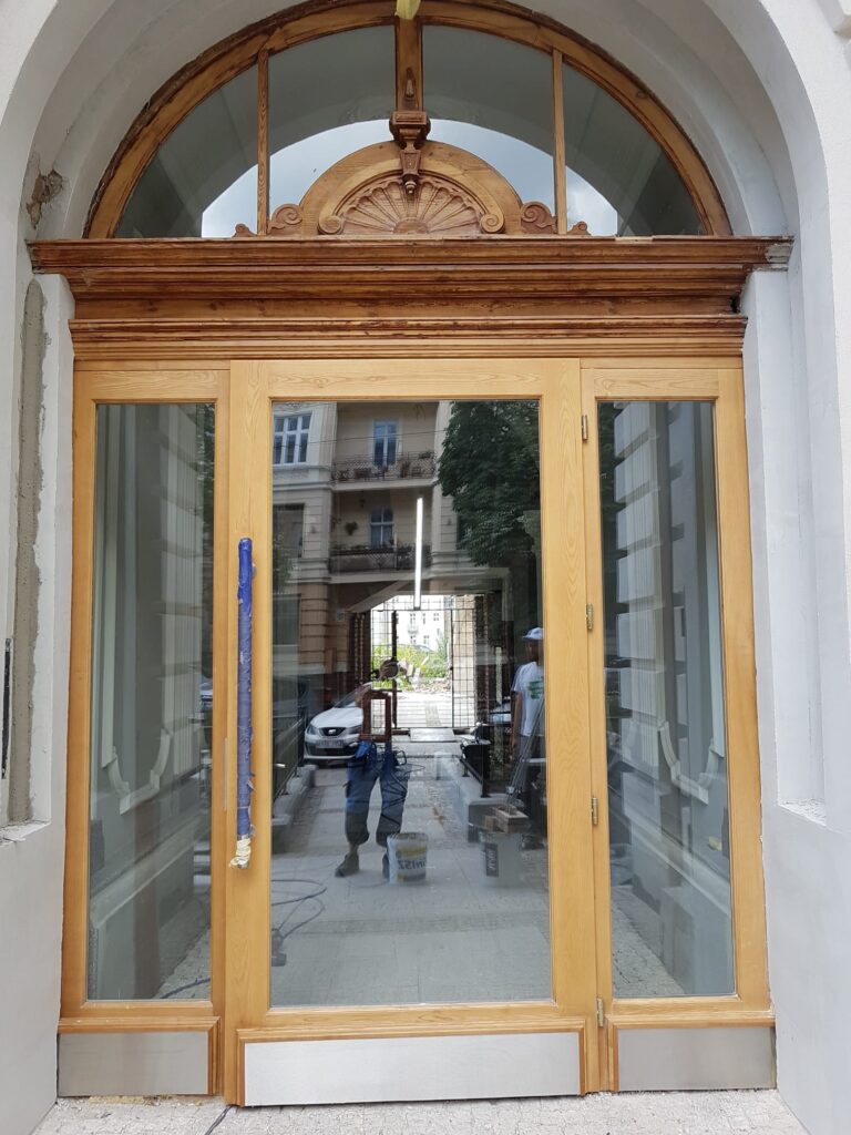 szklane duże drzwi wejściowe z elementami jasnego drewna