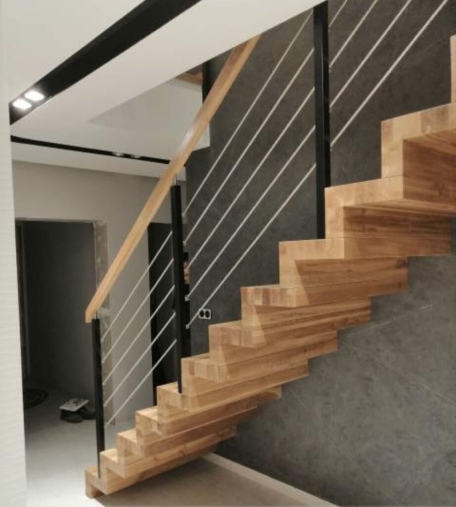 jasne drewniane schody z czarnymi poręczami