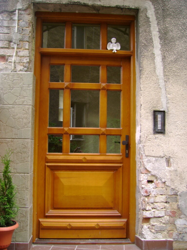 jasne drewniane drzwi wejściowe z elementami szklanymi i domofonem